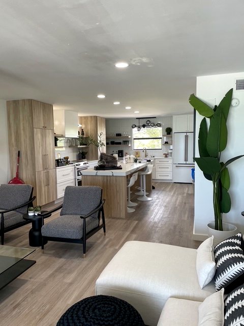 Open-concept kitchen with wood-tone shaker cabinetry opening into the living room