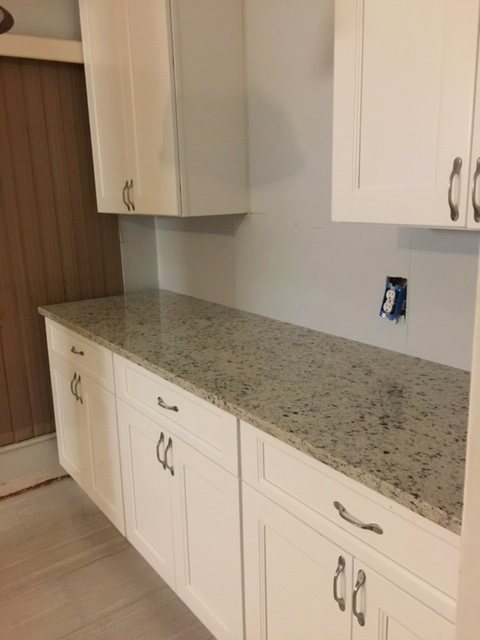 White shaker cabinetry with speckled granite countertops